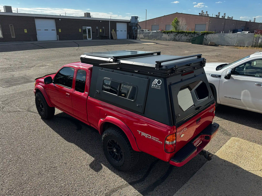 Red 2002 Toyota Tacoma with rooftop tent and camper shell.