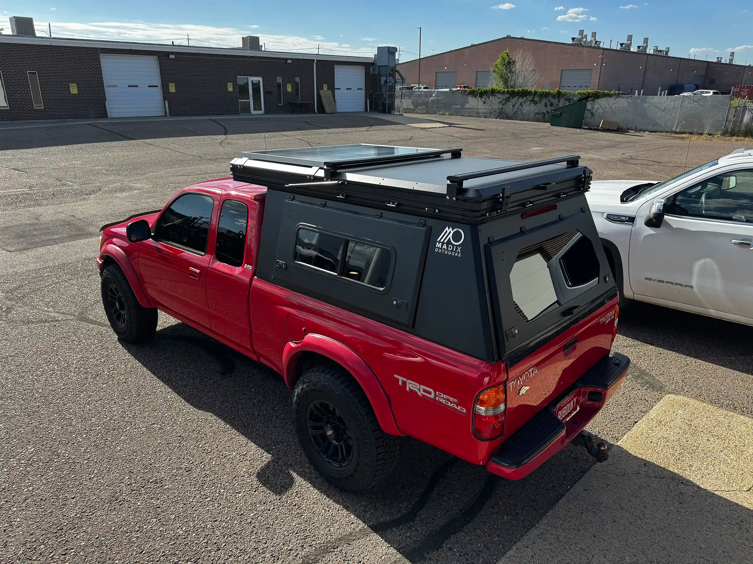 Red 2002 Toyota Tacoma with rooftop tent and camper shell.
