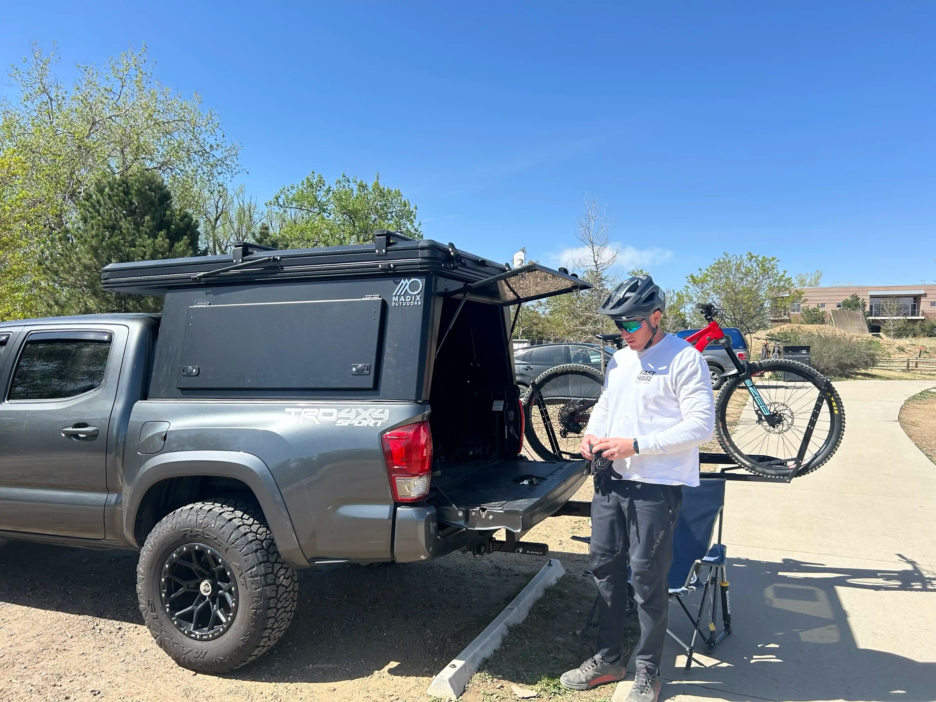 Person standing next to 2017 Toyota Tacoma with truck bed camper system and mountain bike.