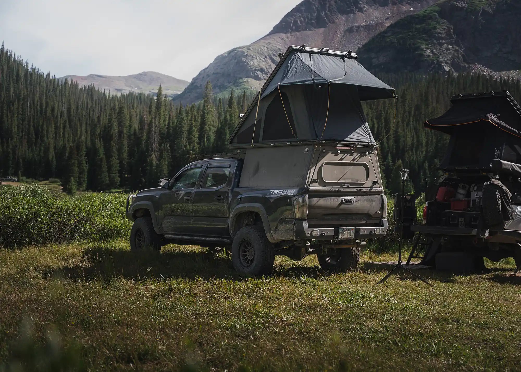 Toyota Tacoma with truck bed camper and rooftop tent in Colorado mountains