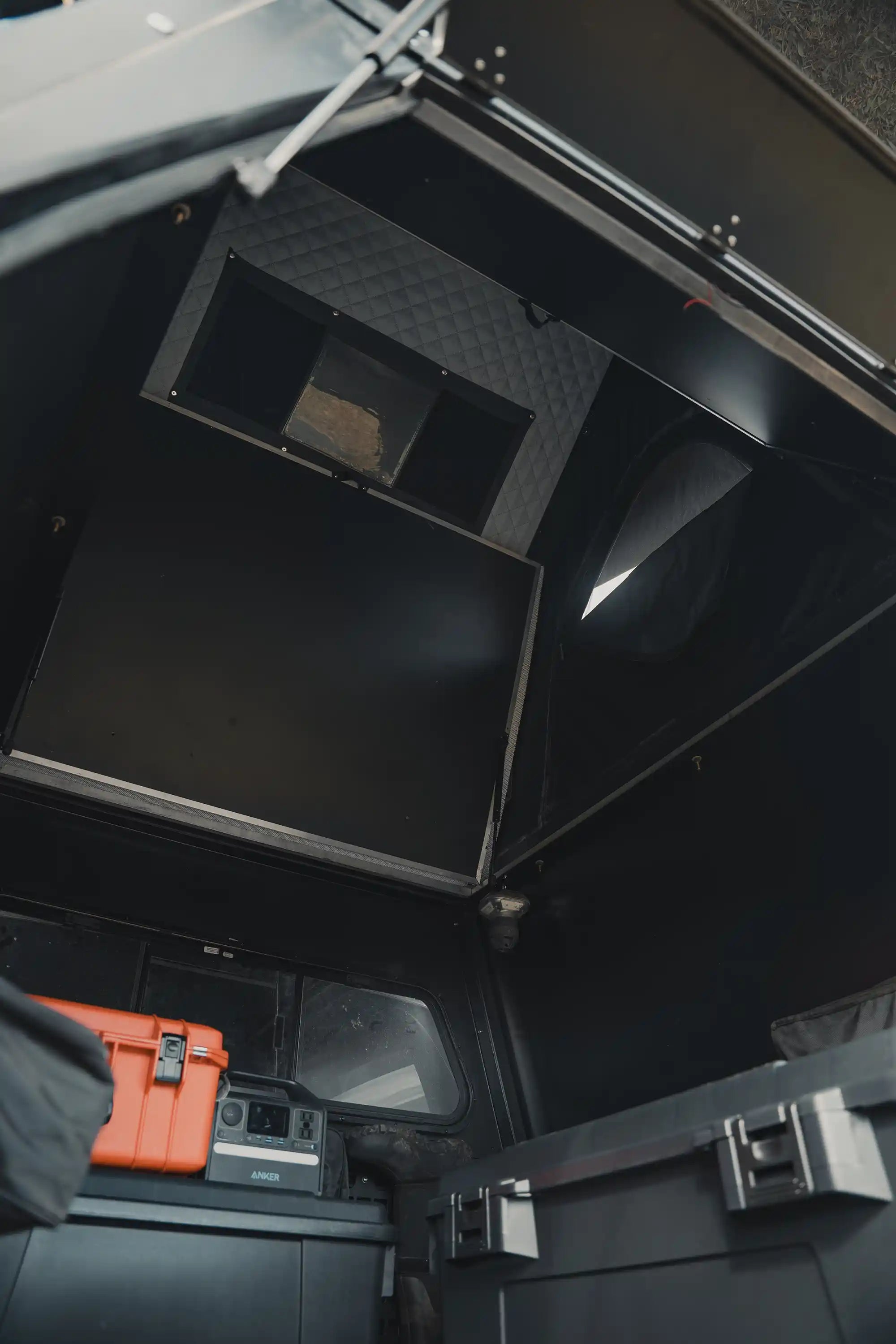 Interior of truck bed camper showing standing height interior with overland gear.
